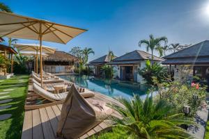 an image of a resort pool with chairs and umbrellas at EHOA BALI Nyanyi Boutique Hotel - In front of entrance to NUANU in Tanah Lot