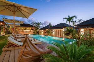 a swimming pool with lounge chairs and an umbrella at EHOA BALI Nyanyi Boutique Hotel - In front of entrance to NUANU in Tanah Lot