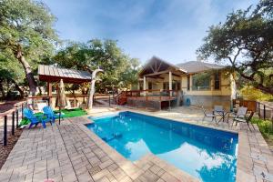 a swimming pool with chairs and a house at Captivating Cottage in New Braunfels