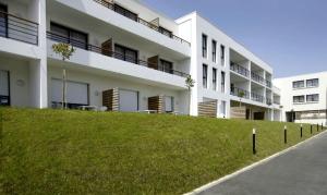 a white building with a grassy hill in front of it at Résidence Odalys Archipel in La Rochelle