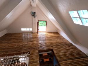 an attic room with wooden floors and a window at L'Astrolabe - Tiny House in Baras