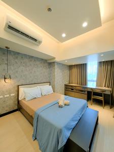 een slaapkamer met een bed met een blauwe deken en een bureau bij Grand Deluxe 3BR with Bathtub in Uptown BGC in Manilla