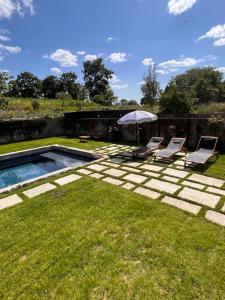 a backyard with a swimming pool and two chairs and an umbrella at Domaine du tertre ychot in Dol-de-Bretagne