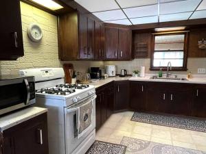 a kitchen with wooden cabinets and a stove top oven at Entire Home in Buffalo - 6 Guests 3 Bedroom 1 Bath - Convenient Location 7 mins from Airport in Buffalo