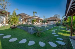 a garden with white stepping stones on the grass at EHOA BALI Nyanyi Boutique Hotel - In front of entrance to NUANU in Tanah Lot