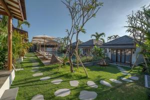 a garden with white stepping stones in a resort at EHOA BALI Nyanyi Boutique Hotel - In front of entrance to NUANU in Tanah Lot