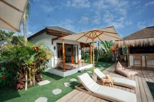a backyard with a deck with chairs and an umbrella at EHOA BALI Nyanyi Boutique Hotel - In front of entrance to NUANU in Tanah Lot