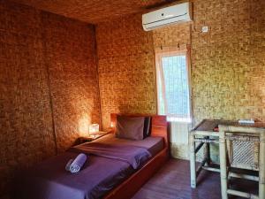 a bedroom with a bed and a window with a fan at Old Village Gili Air in Gili Air