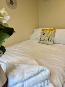 a white bed with a pillow and towels on it at Beautiful Bijou Bungalow in Gloucester