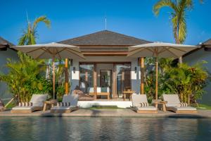a villa with a bed and umbrellas next to a pool at EHOA BALI Nyanyi Boutique Hotel - In front of entrance to NUANU in Tanah Lot