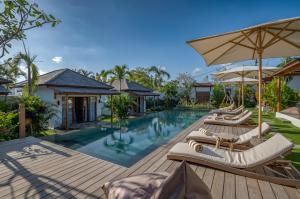 an outdoor pool with lounge chairs and an umbrella at EHOA BALI Nyanyi Boutique Hotel - In front of entrance to NUANU in Tanah Lot