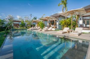 a swimming pool with white chairs and a house at EHOA BALI Nyanyi Boutique Hotel - In front of entrance to NUANU in Tanah Lot