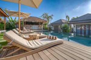 an outdoor deck with lounge chairs and a swimming pool at EHOA BALI Nyanyi Boutique Hotel - In front of entrance to NUANU in Tanah Lot