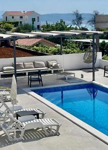 a swimming pool with chaises and chairs next to at Apartments ŽAJA in Seget Vranjica