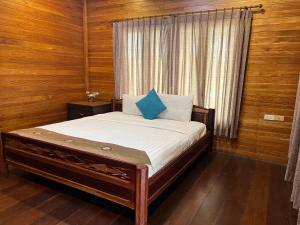 uma cama num quarto com paredes de madeira e uma janela em Sirilagoona Home Resort em Nong Prue