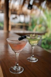 two cocktails sitting on a wooden table at EHOA BALI Nyanyi Boutique Hotel - In front of entrance to NUANU in Tanah Lot