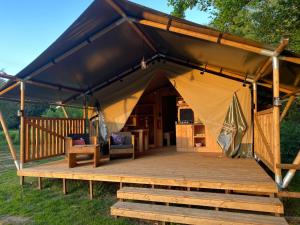 a gazebo with a table and chairs on a wooden deck at Luxury Safari Tents at Moulin Du Pommier Glamping & Camping in Saulgond