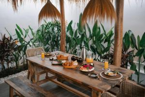 a wooden table with food on it with plants at EHOA BALI Nyanyi Boutique Hotel - In front of entrance to NUANU in Tanah Lot