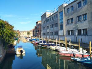 um grupo de barcos ancorados num canal ao lado de edifícios em Immersa nel verde em Veneza