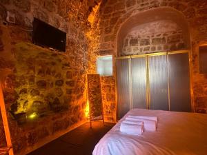 1 dormitorio con 1 cama en una pared de piedra en Paşaoğlu Konağı & Boutique hotel en Mardin