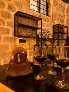 três copos de vinho sentados numa mesa com uma garrafa de vinho em Paşaoğlu Konağı & Boutique hotel em Mardin