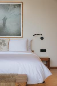 a bedroom with a white bed with a picture on the wall at Sage Villas Bingin in Uluwatu