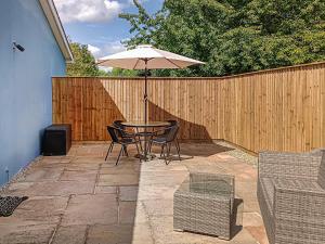 a patio with a table with an umbrella and chairs at The Honey House in Eastry