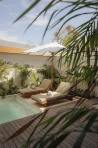 a pool with two lounge chairs and an umbrella at Sage Villas Bingin in Uluwatu