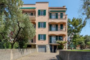 an apartment building with green shutters and trees at Residence Mizar 2 in Pietra Ligure