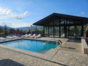 a house with a swimming pool and a pavilion at WhiteWood Cottages in Bukovel