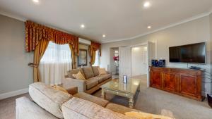 a living room with two couches and a flat screen tv at Prince's Gate Hotel in Rotorua