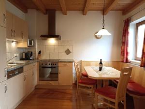 una cocina con mesa y sillas y una cocina con fregadero y fogones. en Haus zur Mühle, en Ried im Oberinntal
