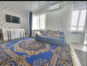 ein Wohnzimmer mit einem blauen Sofa und einem Teppich in der Unterkunft м. Харьковская, ул. Вишняковская in Kiew