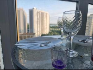 einen Tisch mit Weingläsern und Stadtblick in der Unterkunft м. Харьковская, ул. Вишняковская in Kiew