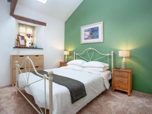 a bedroom with a white bed and a green wall at Lifton Hall - The Barn in Lifton