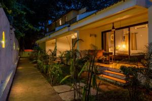 una casa por la noche con un patio y una cama en The Banyan Soul, en Anjuna