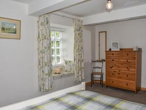 a bedroom with a bed and a dresser and a window at 1 The Old Corn Mill in Middleham