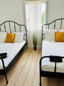 two beds with orange and white pillows in a room at Tiny house 4 min drive to Cdg airport in Roissy-en-France