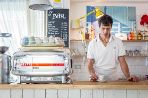 een man die in een keuken een kopje koffie bereidt bij Piccolo Hotel Kursaal in Cesenatico