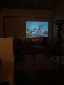 a projection screen with a man on it in a room at Stay JungEui in Seogwipo