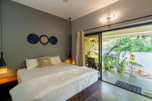 a bedroom with a bed and a large window at The Banyan Soul in Anjuna