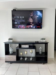 a black entertainment center with a tv on a wall at Modern Condo in Ecovivienda in Tegucigalpa