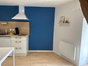 a kitchen with a blue wall and white cabinets at Le Studio 202 in Jasseron