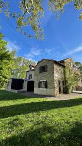 uma velha casa de pedra num campo relvado em Auberge de jeunesse HI Millau La Maladrerie em Millau