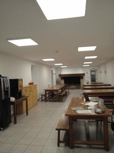 Cette grande chambre comprend des tables, des bancs et un piano. dans l'établissement Auberge de jeunesse HI Millau La Maladrerie, à Millau