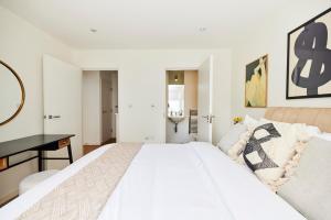 a white bedroom with a large bed and a desk at The Copenhagen Place - Enchanting 2BDR Flat with Balcony in London