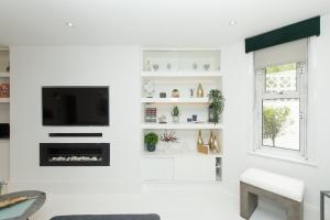 a white living room with a fireplace and a tv at Stylish Apartment with BBQ Kensington in London