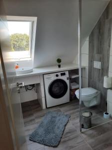a bathroom with a washing machine and a toilet at Villa Mariensiel II in Sande
