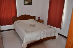 Cama pequeña en habitación con cortinas rojas en Les Gentilhommieres Guest House en Trou aux Biches