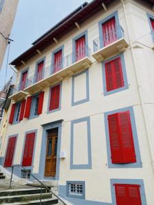 un edificio bianco con porte e finestre rosse di Très bel appartement Cauterets centre 6 places a Cauterets